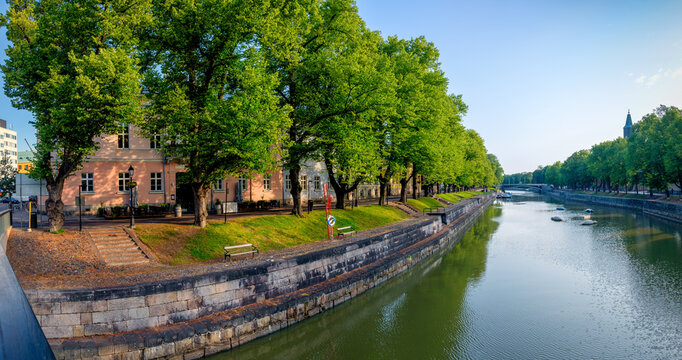 A pedestrian street on a sunny morning photographed from the Library Bridge in Turku, Finland. In the Aura River, the water flows at a slow pace.