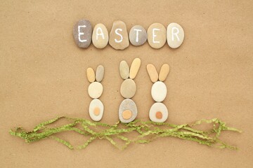 Easter lettering and bunnies from pebbles on craft paper background. Ecological, eco friendly, zero waste nature concept. Flatlay, lay out, top view