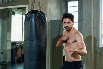 Healthy Caucasian man athletic in sportswear do kickboxing workout and punching boxing bag at gym....