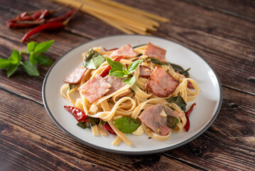 Stir Fried Spicy Spaghetti with ham on wooden background as Thai and Italian fusion food
