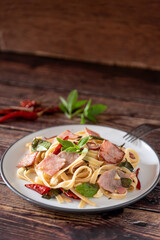Stir Fried Spicy Spaghetti with ham on wooden background as Thai and Italian fusion food