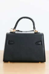 Fashionable women's small leather clutch bag with strap. Isolated on a white background. Traditional clutch bag with a brooch. Gold hardware. Close-up details of the bag. Bottom, handles, strap, clasp