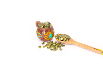 Green Pepitas or Pumpkin Seeds in Orange Pottery Pitcher with a Small Wooden Spoon, Isolated on White