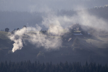 Moutain landscape. Lot of smoke coming out of a chimney from an old house in Lupcina, Romania