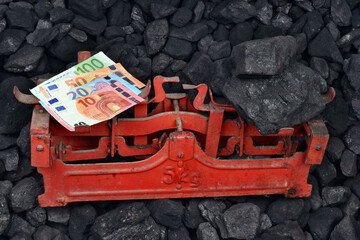 European currency euro and coal showed on weight as concept on coal of mine deposit mineral resources background