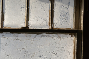 Old fashion window covered in frost with morning light shining thru the glass, dark contrast inside, shadows and light.