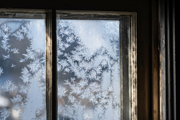 Obraz premium Old fashion window covered in frost with morning light shining thru the glass, dark contrast inside, shadows and light.