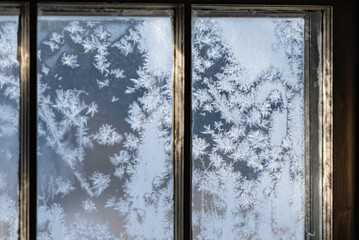 Old fashion window covered in frost with morning light shining thru the glass, dark contrast inside, shadows and light.