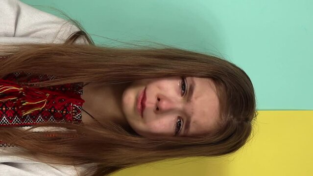 Ukrainian little girl is crying, she is scared on a yellow blue background. Stop the war in Ukraine. Children against war.