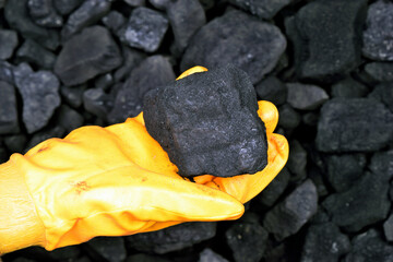 The miner hold and show cube of coal in hand as concept on coal of mine deposit mineral resources background