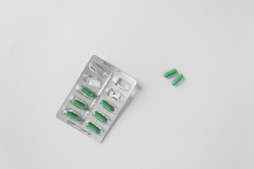 Silver blister with supplements and vitamins in green capsules on white background. Health care...