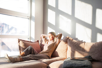 Relaxed middle-aged woman is resting at home sitting on the couch