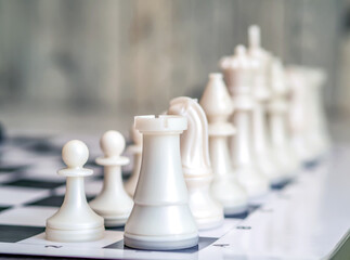 White chess pieces are in the correct order on the chess board. Staunton chess set. Close-up.