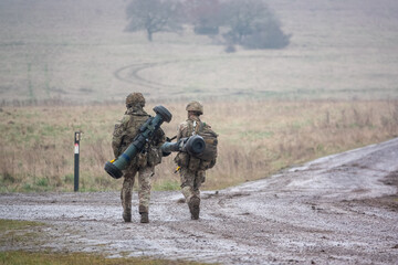 Naklejka premium British army soldiers completing an 8 mile combat fitness test tabbing exercise with fully loaded 25Kg bergen and NLAW (MBT-LAW, RB-57) anti-tank guided missile