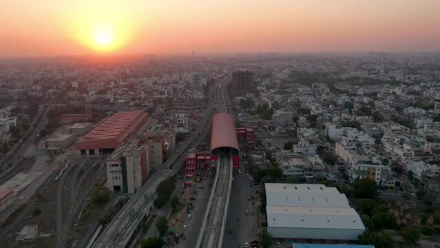 hyperlapse shot at dusk sunset flying over elevated metro track with busy road underneath and metro shed on the side and densely packed houses showing Indian city jaipur lucknow