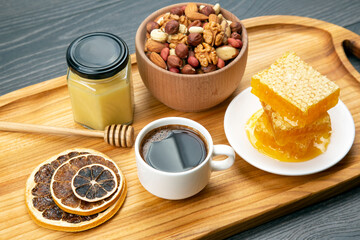 fresh hot coffee with turkey and dried citrus and honeycomb on a kitchen wooden board. useful vitamin food for the human body