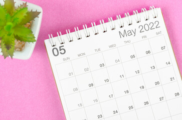 May 2022 desk calendar with plant pot on pink background.