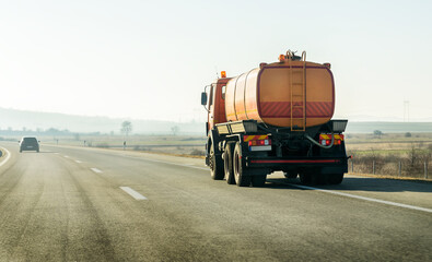 Orange Tank Truck on a highway road under blue sunrise sky