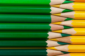 The texture of green wooden pencils with the addition of yellow pencils. copy space