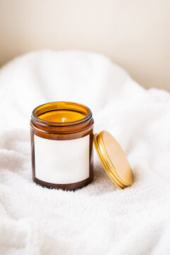 Natural wax candle in brown glass jar with metal lid and white empty clear sticker