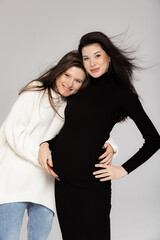 Stylish pregnant brunette in black dress with a throat and her friend