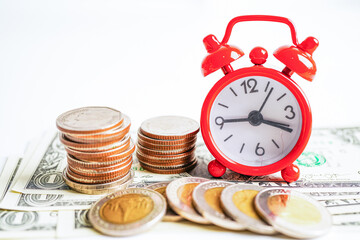 Fototapeta na wymiar .Alarm clock with coins on US dollar banknotes, finance installment loan time.