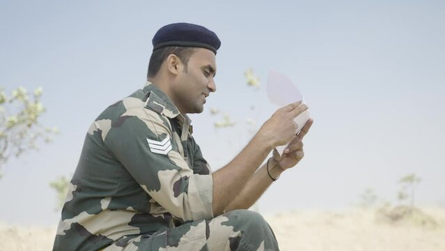 Happy Smiling Young Indian Soldier Reading Letter Or Mail From Family While At Service - Concept Of Remember Family, Good News And Togetherness