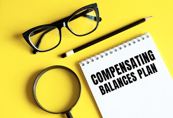 Text Compensating Balances Plan written on a notebook with glasses, magnifying glass and pencil