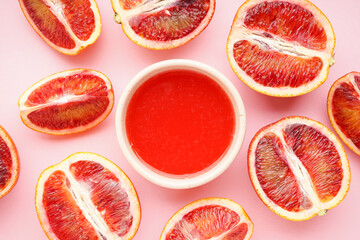 Halves of blood oranges and glass of blood orange juice on a pink background, close-up. Top view.