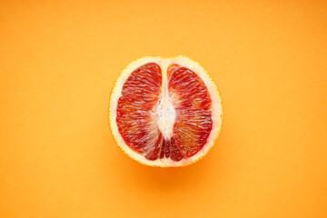 Half of a blood orange on orange background. Top view.