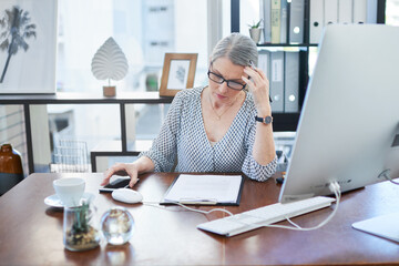 She has a lot to get through today. Shot of a mature businesswoman going through paperwork in an...