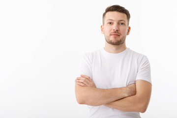 Portrait of a cheerful young man in a white T-shirt on a white background. The guy is standing looking at the camera and smiling.