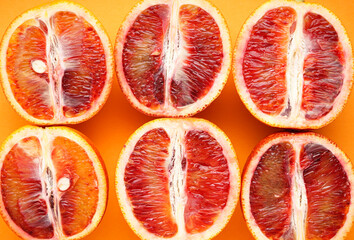 Halves of blood oranges on a orange background, top view. Close-up.