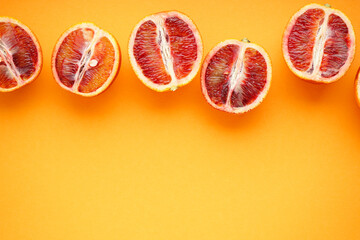 Halves of blood oranges on a orange background with space for text. Top view.