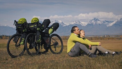 The man and woman travel on mixed terrain cycle touring with bikepacking. The two people journey...