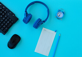 Flat lay home office desk. Workspace with laptop, headphones, pencil and a piece of paper for notes Expenses on blue background. Top view feminine background.