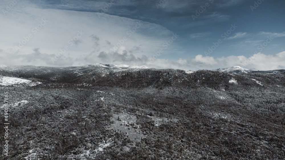 Sticker aerial shot of snowy dry mountains under a cloudy sky