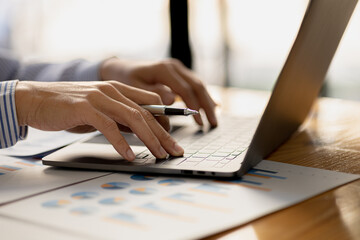 A business man is checking company financial documents and using a laptop to talk to the chief financial officer through a messaging program. Concept of company financial management.