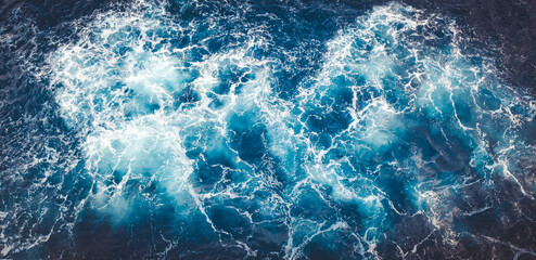 Top view of beautiful foamy textured sea waves in a blue water