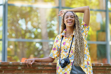 Black woman with African braids, raising her arm in joy. Girl holding a camera.