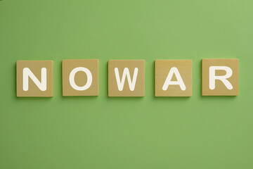 Stop war,no war,peace,freedom,Against World War concept.,white color NO WAR text on wooden cube over green pastel background.,