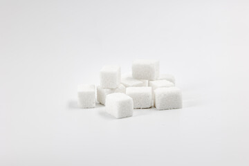 Many cubes of white regular sugar in a heap on a light background isolated
