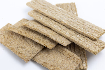 A pile of dry wheat light thin slices of dry diet bread on a white background isolated top view
