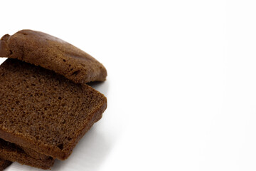 several sliced ​​​​pieces of brown rye natural organic bread lie on top of each other on a white background on the side