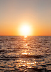 Naklejka na ściany i meble Sunset with yellow sun at the horizon at sea