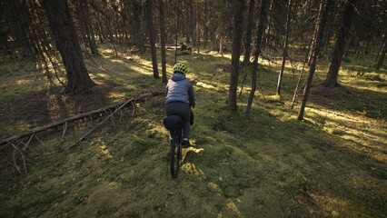 Obraz premium The woman travel on mixed terrain cycle touring with bike bikepacking outdoor. The traveler journey with bicycle bags. Stylish bikepacking, bike, sportswear in green black colors. Magic forest park.