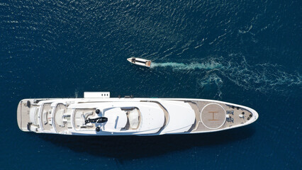 Aerial drone top down photo of large yacht with wooden deck anchored in Aegean island deep blue sea