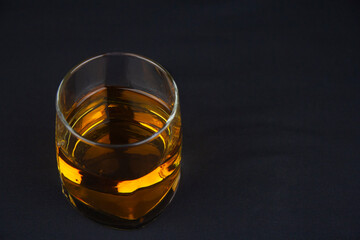 A glass of amber whiskey on a black background