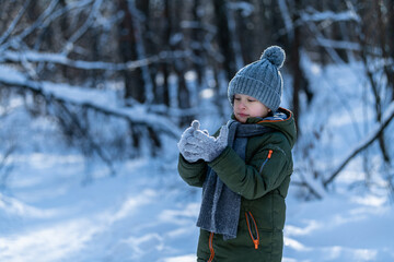 little boy in the woods looking at his snow covered hands