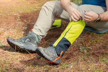 Hiker wears gaiters over trekking boots to protect against water, insects and cold. Clothing and...
